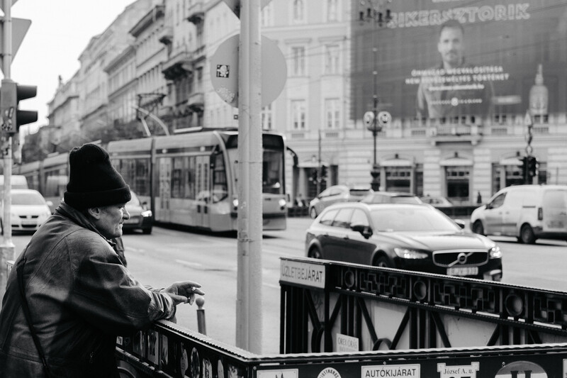 An older man smoking a cigarette in the street.