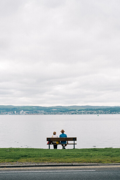 A couple sat on a bench by a lake.
