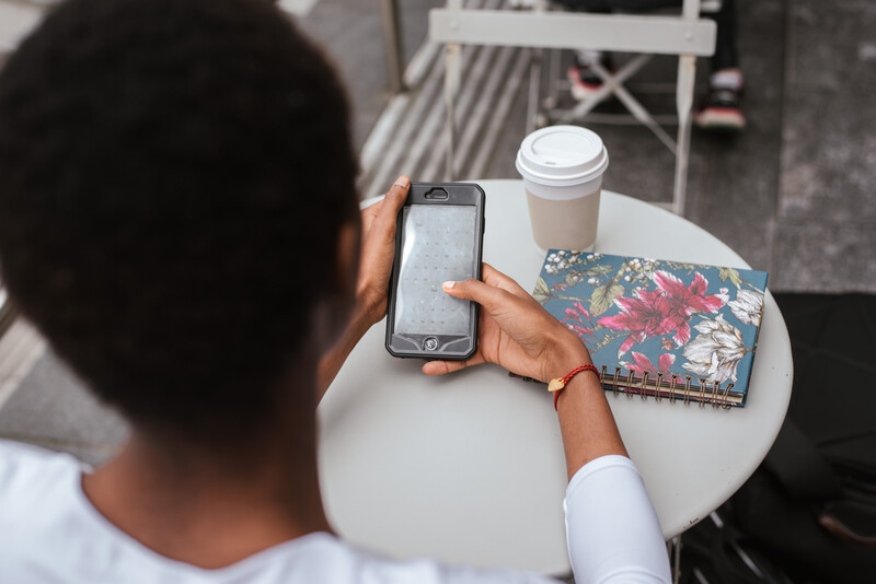 A young woman using her phone at an outdoor cafe.