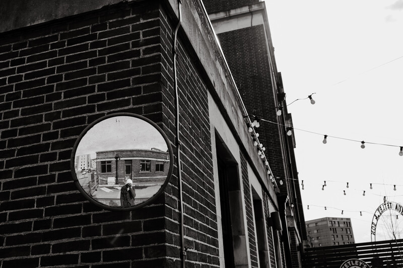 A person taking a self portrait in a mirror outdoors.