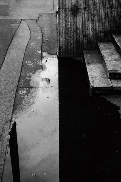 A puddle with a reflection of a wall.