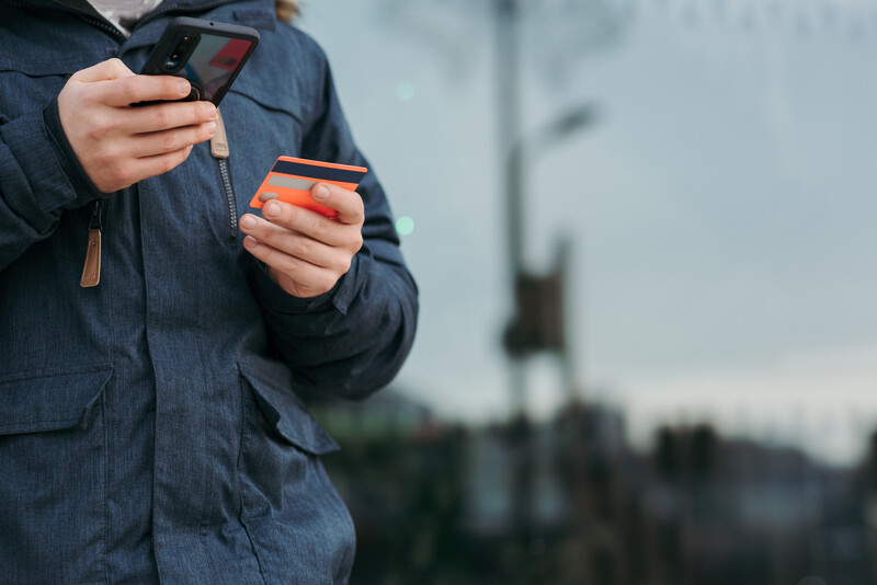 A man holding a mobile phone and a credit card