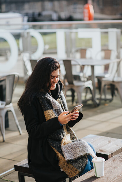 A young woman using her phone at a cafe. 
