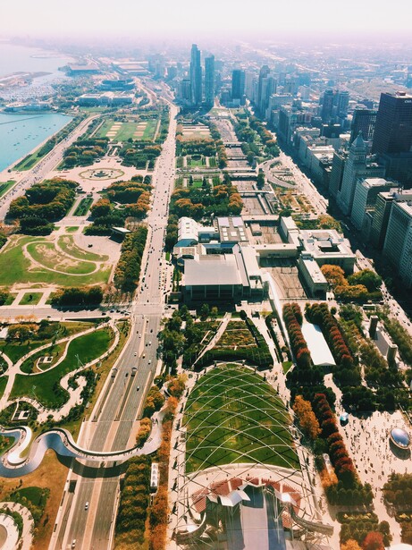 Aerial view of a city skyline with curved highways, green parks, and waterfront along a blue river.