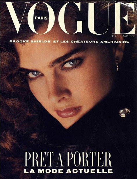 Vogue Paris magazine cover featuring a woman with dark wavy hair and bold eye makeup against a dark background.