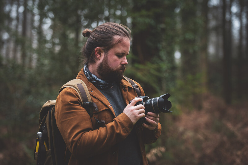 Man in forest holding camera