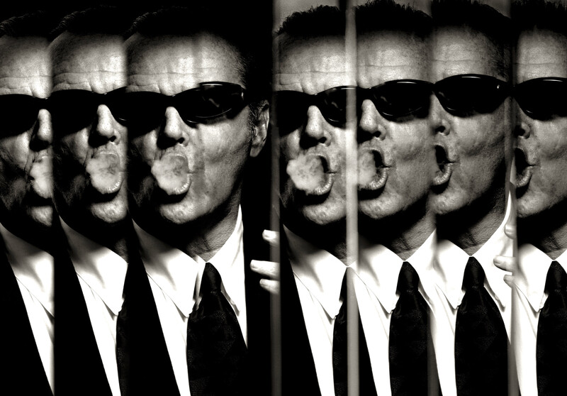 Multiple exposures of a man in sunglasses and dark suit arranged in a grid pattern, creating a mirrored, repetitive composition.