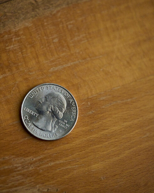 United States quarter coin positioned on wooden surface with natural grain texture.