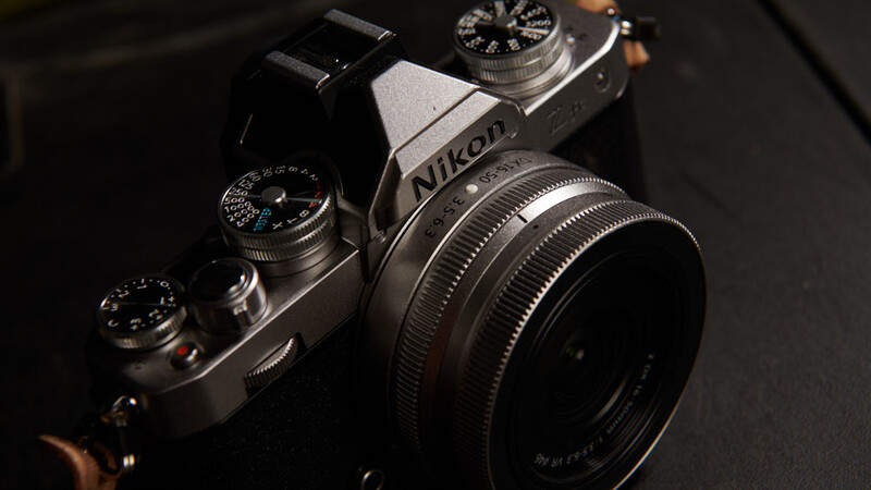 Nikon film camera with rangefinder viewfinder and manual control dials on dark background.