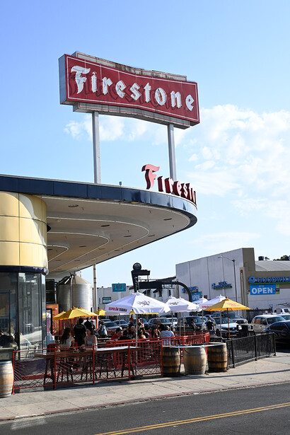 Vintage Firestone tire shop with retro signage and classic cars parked outside.