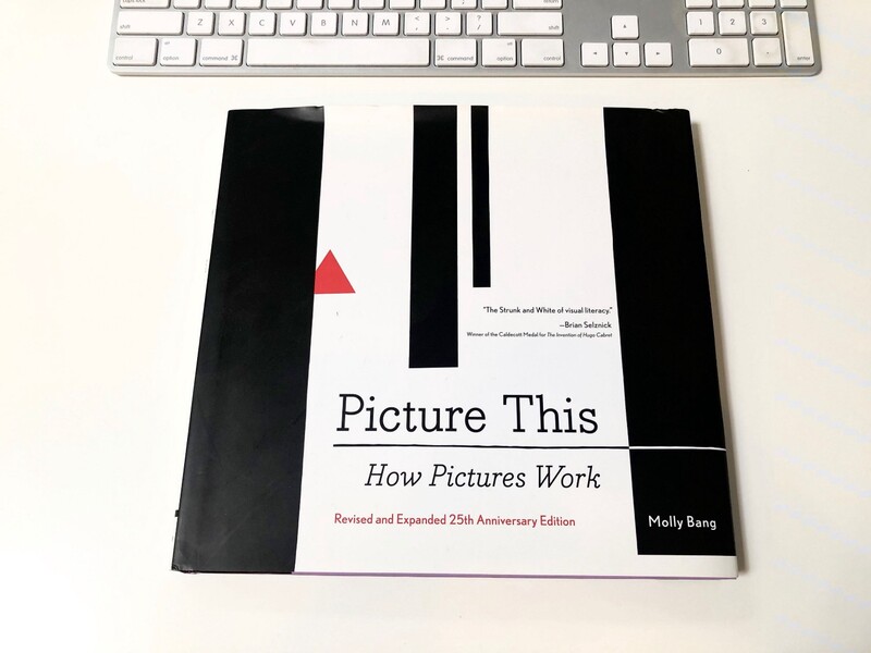 Copy of 'Picture This: How Pictures Work' book displayed on white desk next to keyboard.