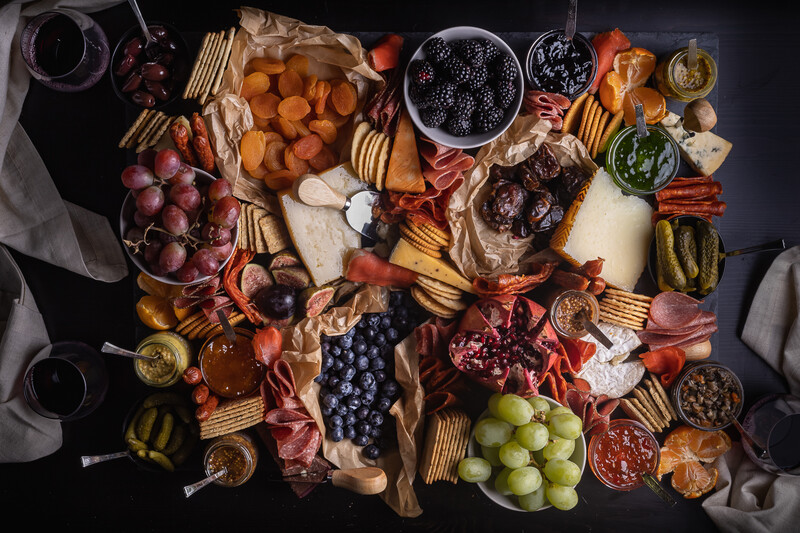 charcuterie board by Jules Sherred with fruits, crackers, meats, cheeses, pickles, and jams.