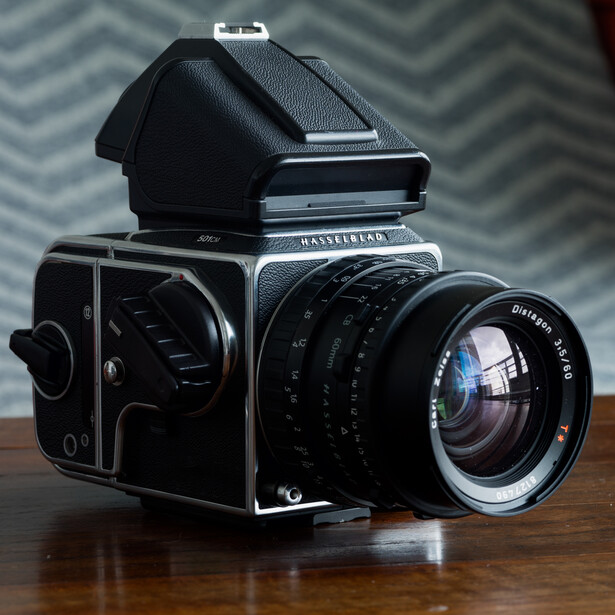 A Hasselblad 500C/M medium format camera with prism viewfinder and Carl Zeiss lens on wooden surface.