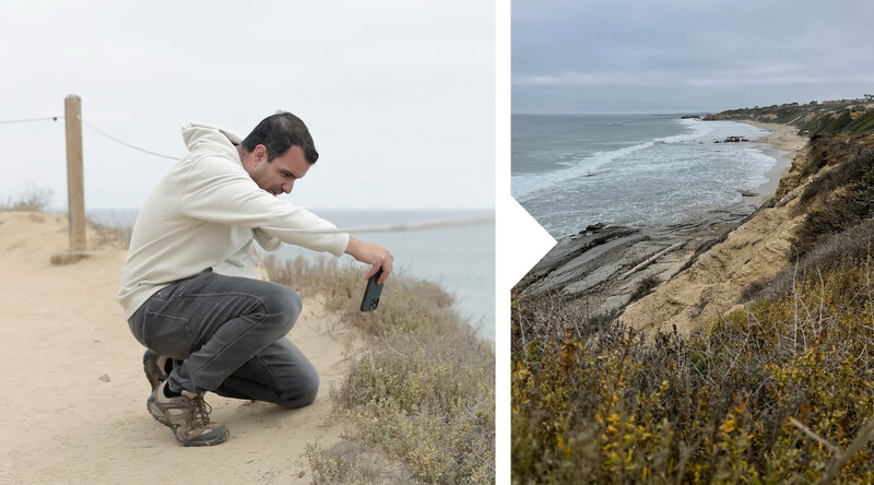 Man crouching on sandy coastal bluff overlooking ocean and beach below.