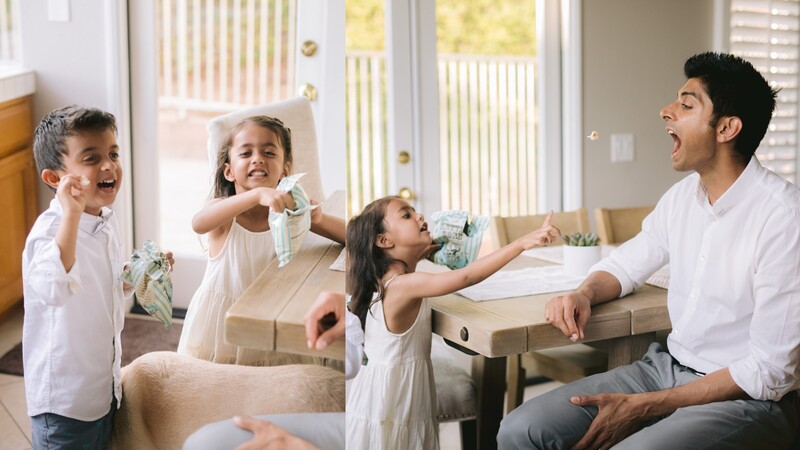 Father and three children playing with toy dinosaurs on a living room sofa.