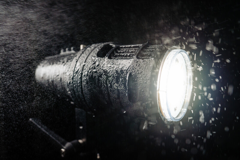 Underwater flashlight covered in sediment particles, its bright white beam cutting through murky water.
