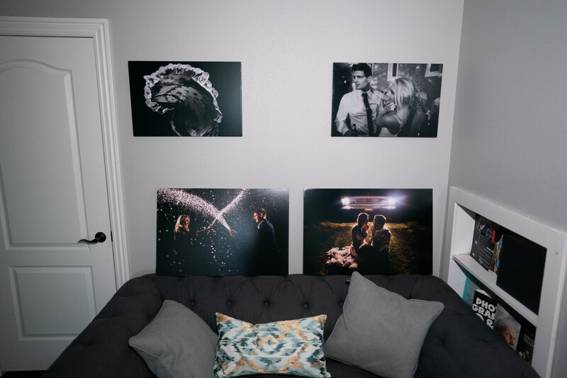 Black and white photography prints displayed on a bedroom wall above a dark couch with pillows.