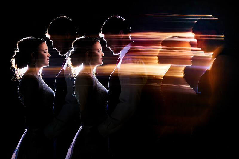 Silhouetted profiles of three people with glowing light streaks emanating from their heads against a dark background.