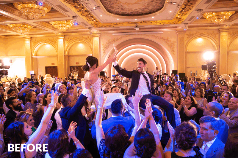 Bride and groom crowd surfing at wedding reception in ornate ballroom.