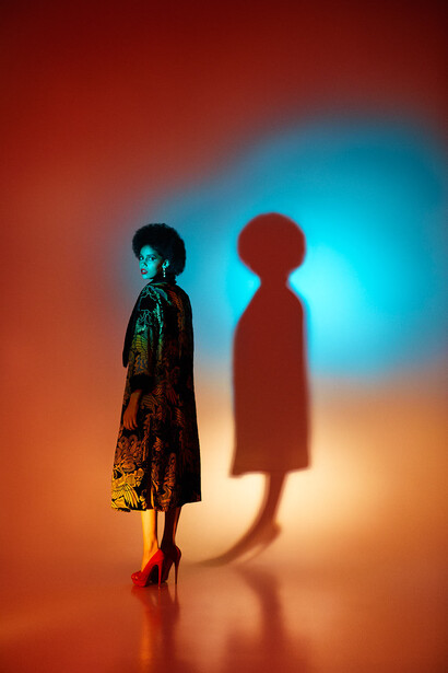 Two silhouetted figures standing against a vibrant gradient backdrop of orange, blue, and golden tones.