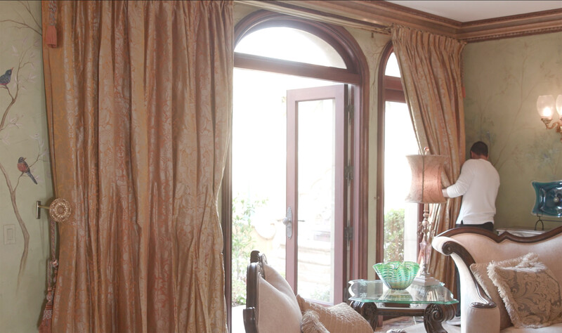 Elegant interior with arched glass doors, sheer curtains, and warm natural lighting from a balcony.