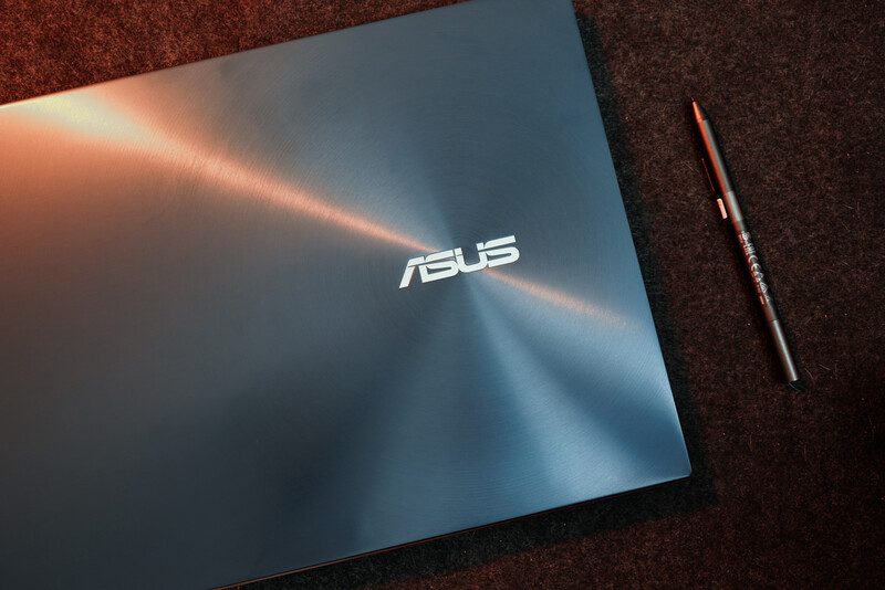 ASUS laptop with brushed metal finish and stylus on textured fabric surface.
