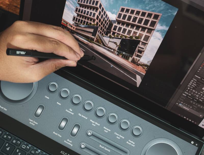 Photographer's hand adjusting a control surface while editing architectural imagery on a monitor.