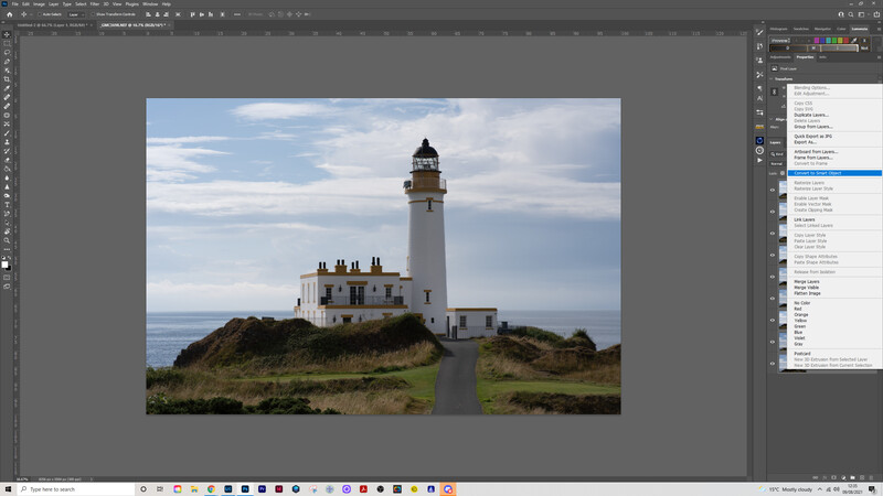 White lighthouse with attached keeper's house on a grassy headland overlooking the sea.