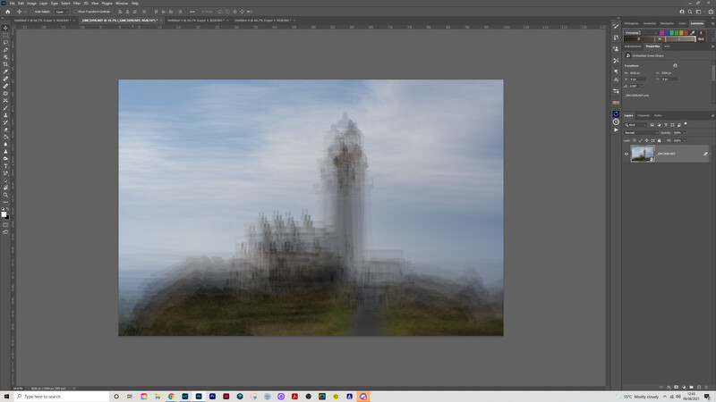 Gothic castle tower shrouded in mist and fog on a hillside under overcast sky.