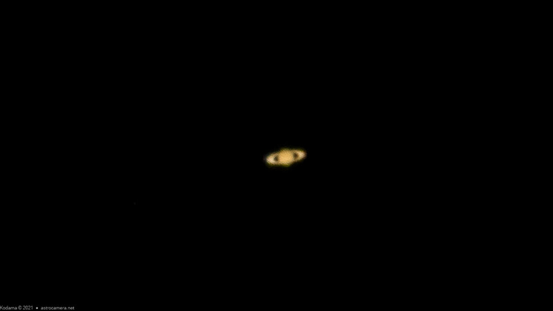 Saturn photographed through a telescope against a black sky, showing the planet's distinctive rings and pale golden disk.