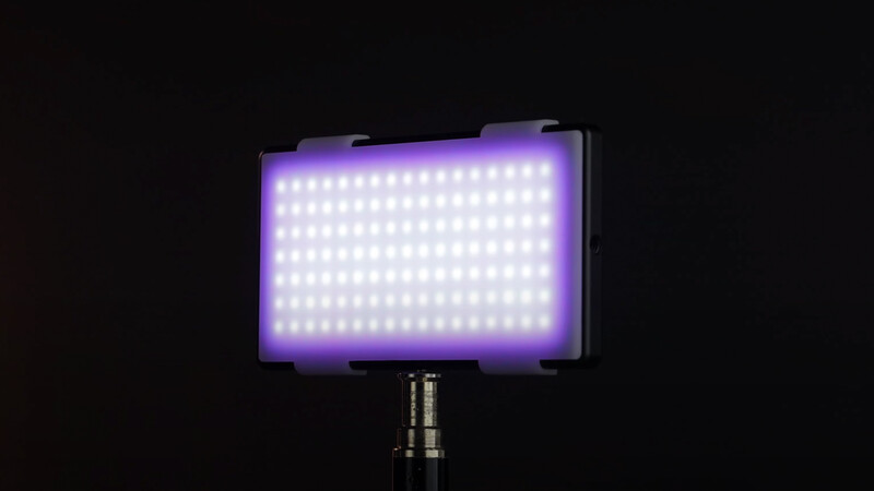 Purple LED panel light mounted on a tripod stand against a black background.