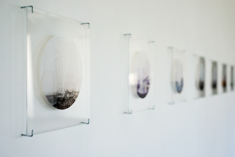 Series of clear acrylic panels mounted on white wall, each containing suspended architectural model or structure with purple and black tones.