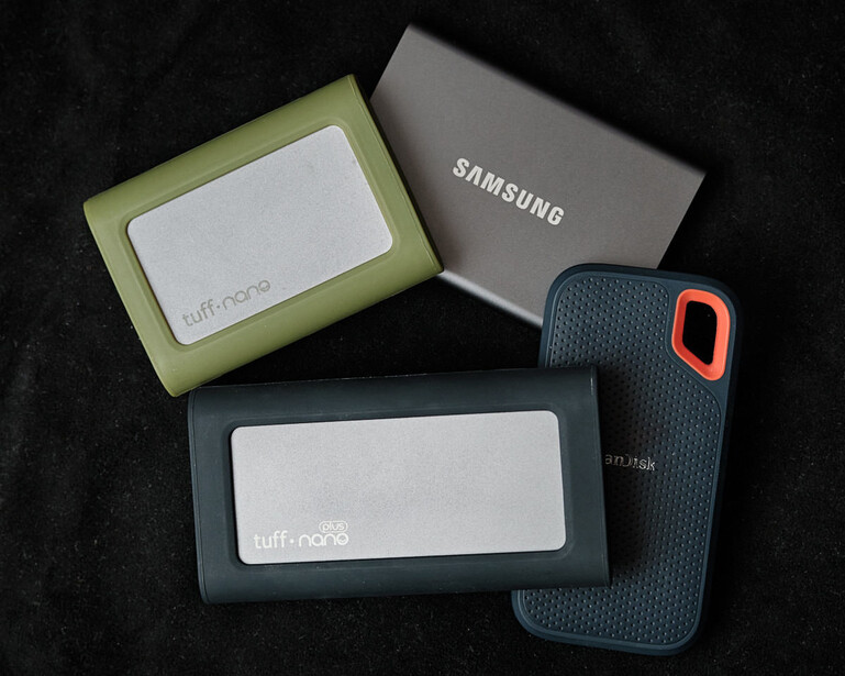 Four protective cases for mobile devices arranged on a black textured surface, including models from Samsung and Spigen brands.