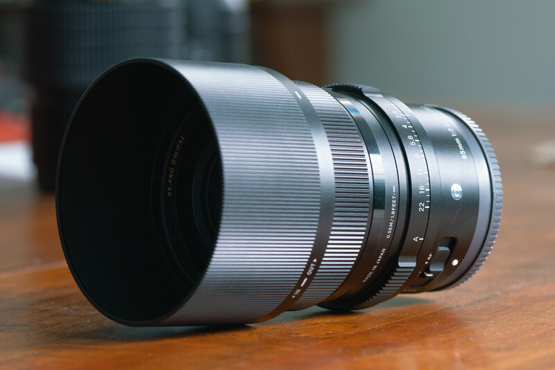 Vintage telephoto lens with silver barrel and black focus ring on wooden surface.