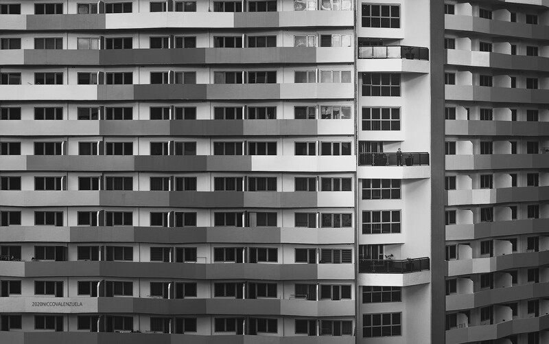 Black and white photograph of two modernist apartment buildings with repetitive window patterns and curved balconies.