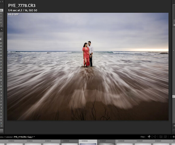 Couple in colorful clothing standing in ocean waves with motion blur effect.