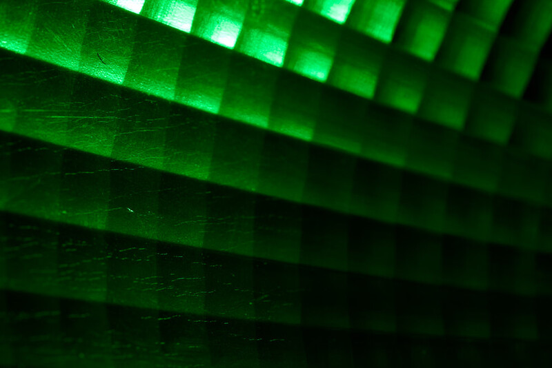Abstract green light pattern with horizontal layered bands and glowing bright rectangles creating geometric shapes.