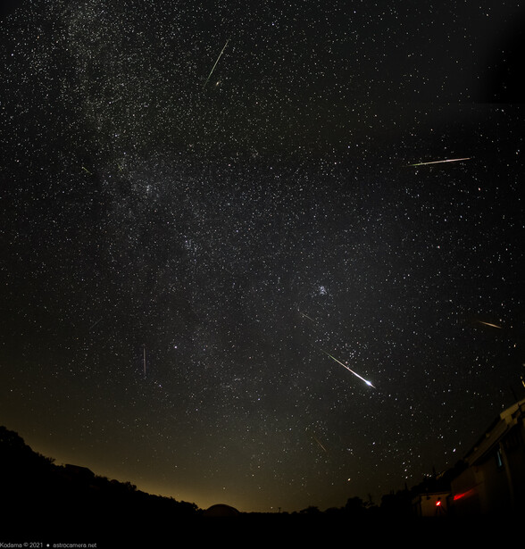 Milky Way galaxy stretching across night sky with multiple meteor streaks and silhouetted landscape horizon.