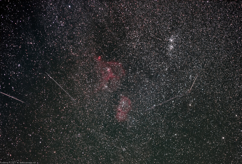 Milky Way galaxy with reddish nebula clouds and meteor streaks across starfield.
