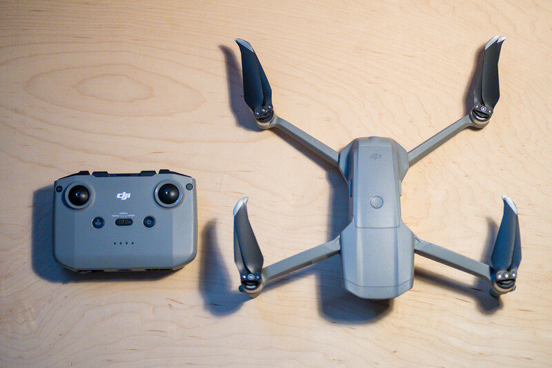 DJI Mini drone with remote controller on wooden surface.