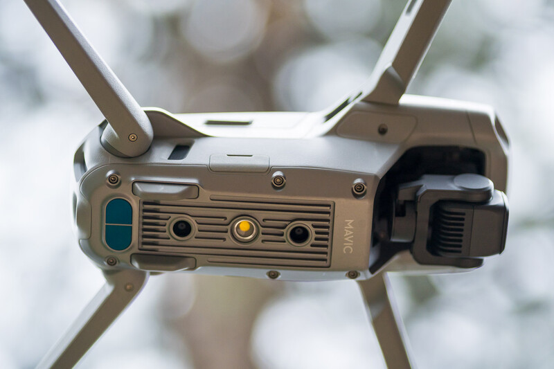 Bottom view of a drone's control unit showing antenna, control buttons, and status indicator lights.