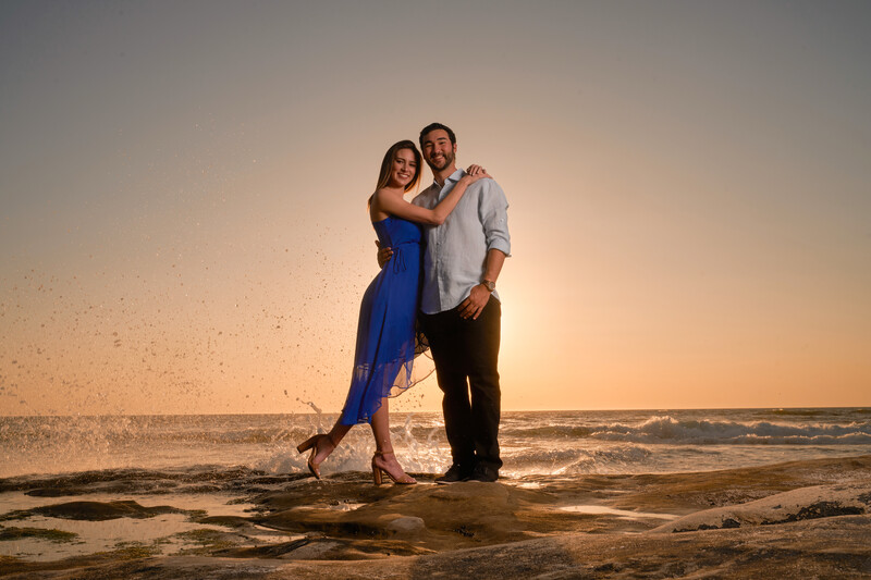Couple posing together on a beach at golden hour sunset.
