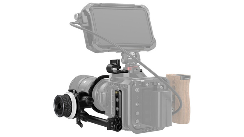 Illustration of a cinema camera with attached follow focus system, monitor, and wooden side handle.