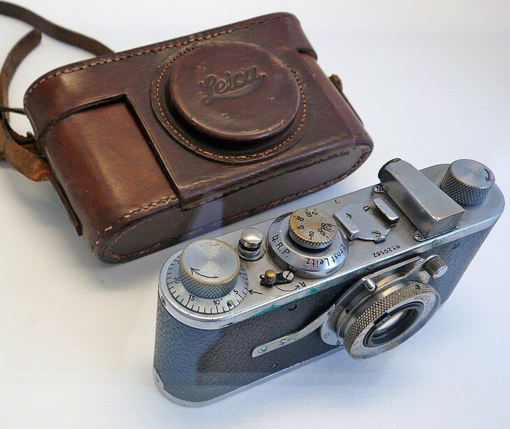 Vintage rangefinder camera in blue with brown leather case and lens cap.