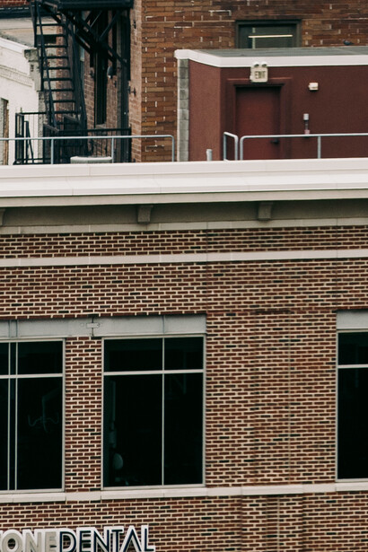 Brick building facade with three large windows and fire escape on upper level.