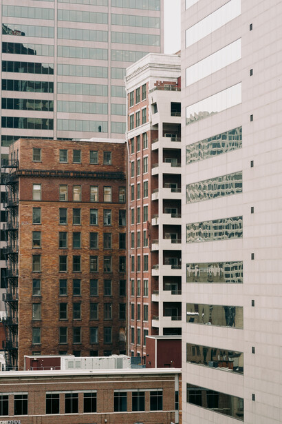Historic brick buildings adjacent to modern glass and concrete skyscrapers in urban architectural composition.