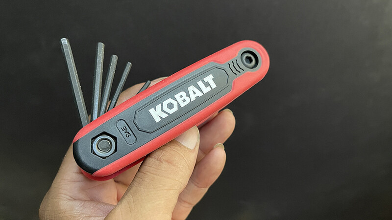 Red and gray Kobalt multi-tool held in hand with allen wrenches extended.