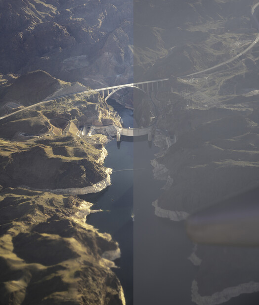 Aerial view of a concrete bridge spanning a deep gorge with forested cliffs and a river far below.