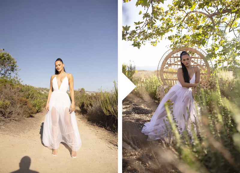 Woman in white flowing dress standing on sandy path with desert brush and hills behind her.