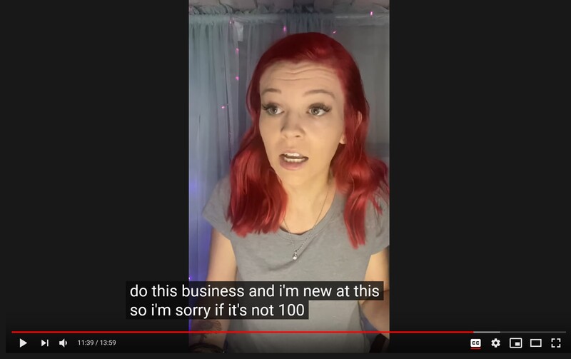 Screenshot of a video featuring a person with red hair speaking directly to camera indoors.